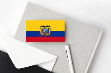 Minimalist harf geçmişinde Ekvador bayrağı. Beyaz kalemli ve defterli ulusal davetiye zarfı. İletişim konsepti.