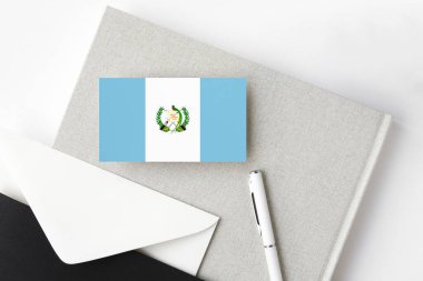 Minimalist arka planda Guatemala bayrağı. Beyaz kalemli ve defterli ulusal davetiye zarfı. İletişim konsepti.