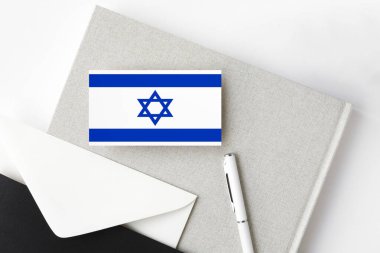 Minimalist arka planda İsrail bayrağı. Beyaz kalemli ve defterli ulusal davetiye zarfı. İletişim konsepti.
