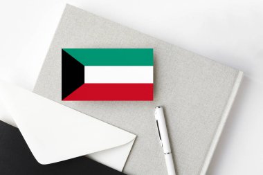 Minimalist arka planda Kuveyt bayrağı. Beyaz kalemli ve defterli ulusal davetiye zarfı. İletişim konsepti.