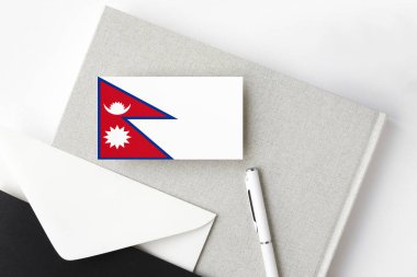 Minimalist harf geçmişinde Nepal bayrağı. Beyaz kalemli ve defterli ulusal davetiye zarfı. İletişim konsepti.