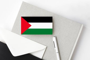 Minimalist arkaplanda Filistin bayrağı var. Beyaz kalemli ve defterli ulusal davetiye zarfı. İletişim konsepti.