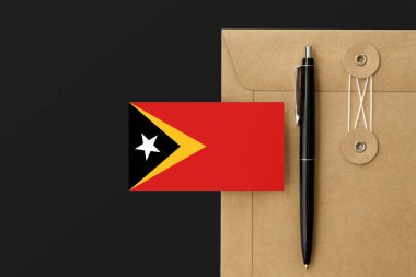Mektup ve siyah kalem arkaplanda Doğu Timor bayrağı var. Ulusal davet konsepti. Eğitim teması için davet.