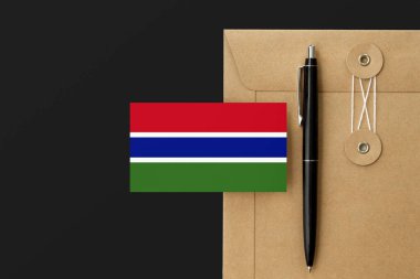 Zarf zarfında Gambiya bayrağı ve siyah kalem geçmişi. Ulusal davet konsepti. Eğitim teması için davet.