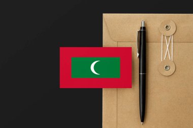 Mektup ve siyah kalem arkaplanda Maldivler bayrağı var. Ulusal davet konsepti. Eğitim teması için davet.
