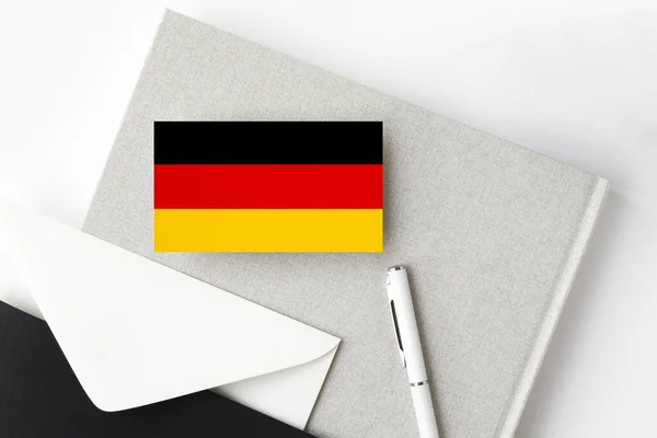 德国国旗上的简约字母背景 有白色钢笔和笔记本的国家邀请函 传播概念 — 图库照片