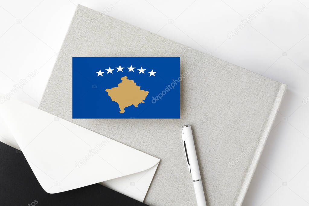 Kosovo flag on minimalist letter background. National invitation envelope with white pen and notebook. Communication concept.