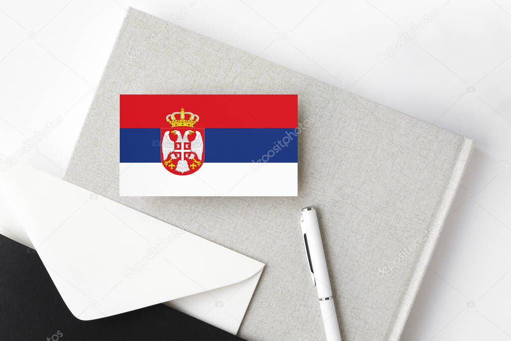 Serbia flag on minimalist letter background. National invitation envelope with white pen and notebook. Communication concept.