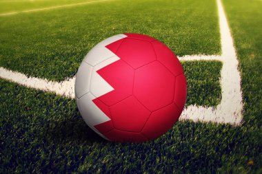 Köşede top, saha arkasında bahreyn bayrağı. Ulusal futbol teması yeşil çimlerde.