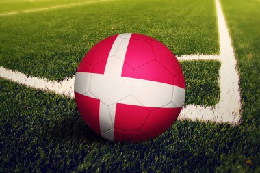 Danimarka bayrağı köşe vuruşunda, futbol sahasında arka planda. Ulusal futbol teması yeşil çimlerde.