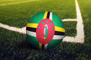Dominica bayrağı köşe vuruşunda, futbol sahasında. Ulusal futbol teması yeşil çimlerde.