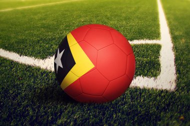 Doğu Timor bayrağı köşe vuruşu pozisyonunda, futbol sahasında. Ulusal futbol teması yeşil çimlerde.