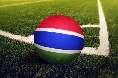 Gambiya bayrağı köşede, futbol sahasında. Ulusal futbol teması yeşil çimlerde.