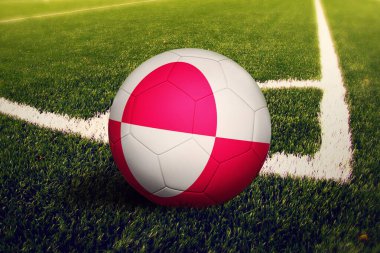 Top Grönland bayrağında, köşe vuruşunda, futbol sahasında. Ulusal futbol teması yeşil çimlerde.