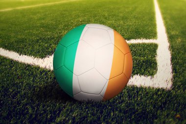 İrlanda bayrağı köşe vuruşu pozisyonunda, futbol sahasında. Ulusal futbol teması yeşil çimlerde.
