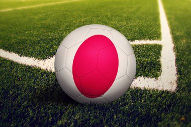 Japon bayrağı köşe vuruşunda, futbol sahasında. Ulusal futbol teması yeşil çimlerde.