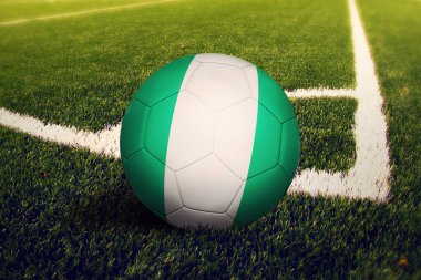Nijerya bayrağı köşe vuruşunda top, futbol sahasında arka plan. Ulusal futbol teması yeşil çimlerde.