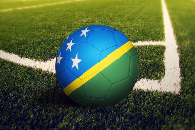 Solomon Adaları topu köşeye sıkıştırdı, futbol sahasının arka planında. Ulusal futbol teması yeşil çimlerde.