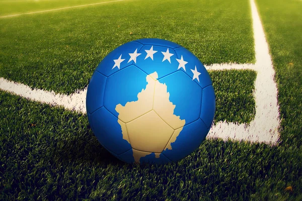 Kosovo flag on ball at corner kick position, soccer field background. National football theme on green grass.