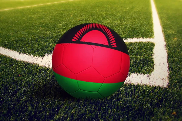 Malawi flag on ball at corner kick position, soccer field background. National football theme on green grass.