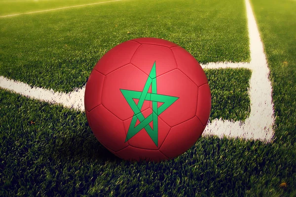 Morocco flag on ball at corner kick position, soccer field background. National football theme on green grass.