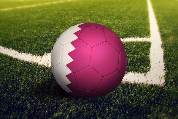 Köşe vuruşunda top Katar bayrağında, futbol sahasında arka plan. Ulusal futbol teması yeşil çimlerde.