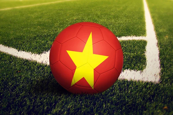 Vietnam flag on ball at corner kick position, soccer field background. National football theme on green grass.