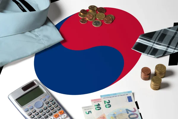 South Korea flag on minimal money concept table. Coins and financial objects on flag surface. National economy theme.