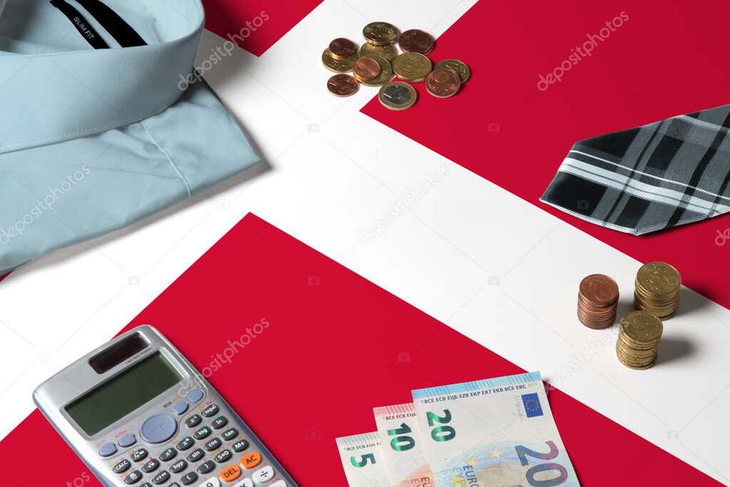 Denmark flag on minimal money concept table. Coins and financial objects on flag surface. National economy theme.
