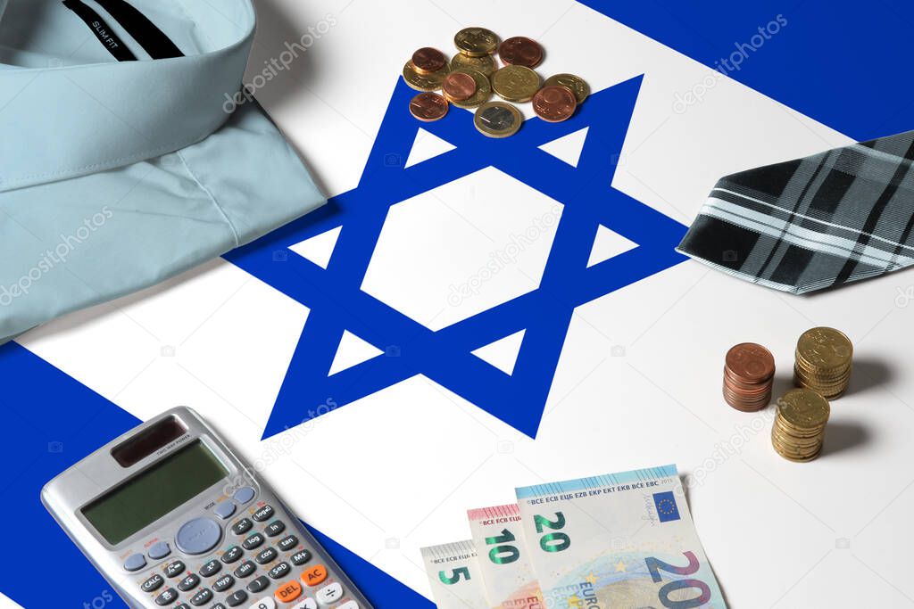Israel flag on minimal money concept table. Coins and financial objects on flag surface. National economy theme.