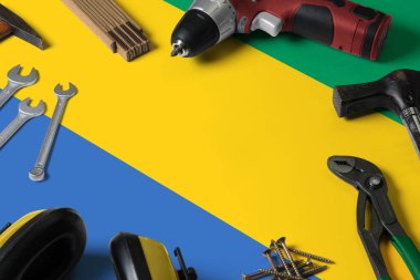 Tamir aletleri tahta masa arka planında Gabon bayrağı. Ulusal nesnelerle mekanik servis teması.