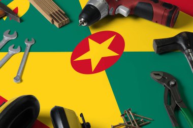 Tamir aracı kavramının tahta masa arka planında Grenada bayrağı. Ulusal nesnelerle mekanik servis teması.