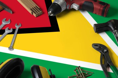 Tamir aleti kavramının tahta masa arka planında Guyana bayrağı. Ulusal nesnelerle mekanik servis teması.