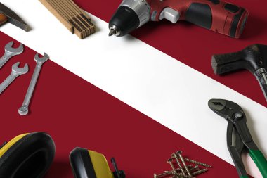 Onarım aracı kavramı üzerine Letonya bayrağı, tahta masa arka planı. Ulusal nesnelerle mekanik servis teması.