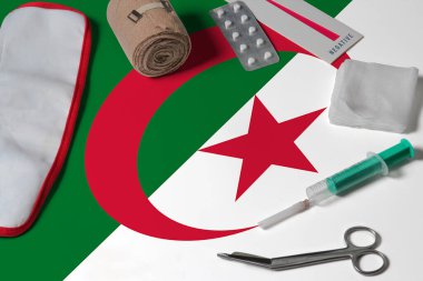 Ahşap masa arkasında ilk yardım çantasıyla Cezayir bayrağı. Ulusal sağlık sistemi konsepti, tıbbi tema.