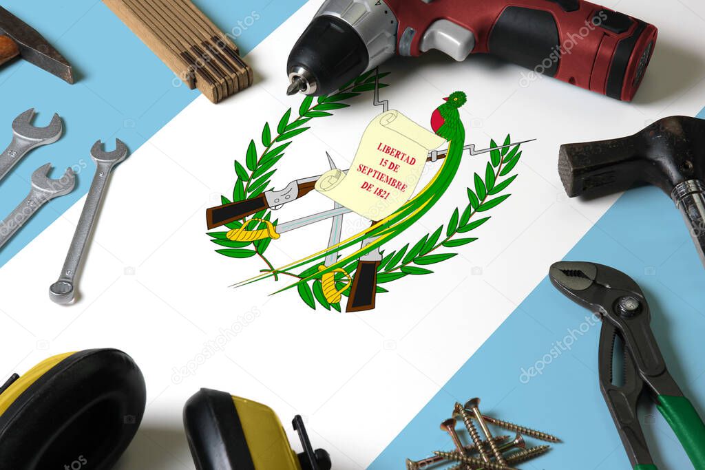 Guatemala flag on repair tool concept wooden table background. Mechanical service theme with national objects.