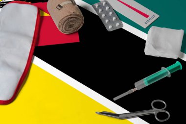 Ahşap masa arkasında ilk yardım çantasıyla Mozambik bayrağı. Ulusal sağlık sistemi konsepti, tıbbi tema.