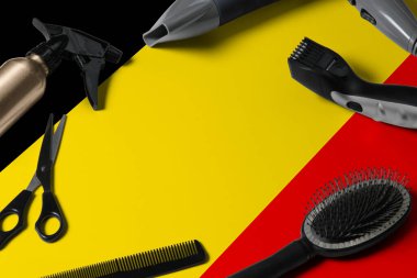 Saç kesme aletli Belçika bayrağı. Ulusal bir ahşap arka planda güzellik salonunun masasında taraklar, makas ve kuaför aletleri.
