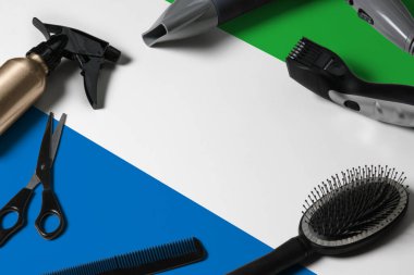 Saç kesme aletleriyle Sierra Leone bayrağı. Ulusal bir ahşap arka planda güzellik salonunun masasında taraklar, makas ve kuaför aletleri.