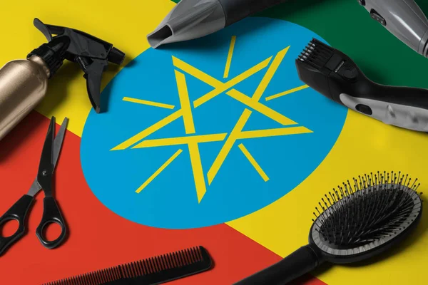 Ethiopia flag with hair cutting tools. Combs, scissors and hairdressing tools in a beauty salon desktop on a national wooden background.