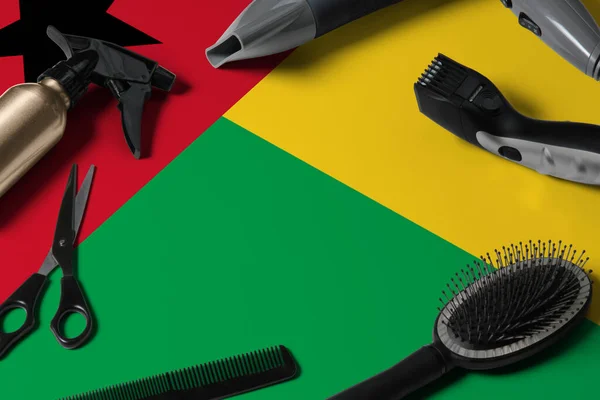 Guinea flag with hair cutting tools. Combs, scissors and hairdressing tools in a beauty salon desktop on a national wooden background.
