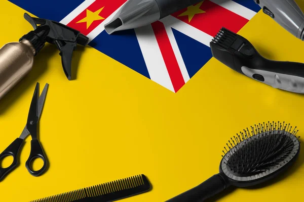 Niue flag with hair cutting tools. Combs, scissors and hairdressing tools in a beauty salon desktop on a national wooden background.