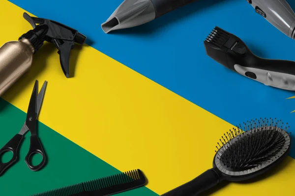 Rwanda flag with hair cutting tools. Combs, scissors and hairdressing tools in a beauty salon desktop on a national wooden background.