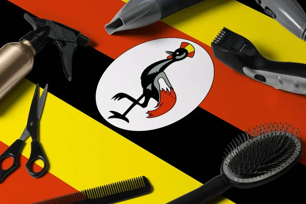 Uganda flag with hair cutting tools. Combs, scissors and hairdressing tools in a beauty salon desktop on a national wooden background.