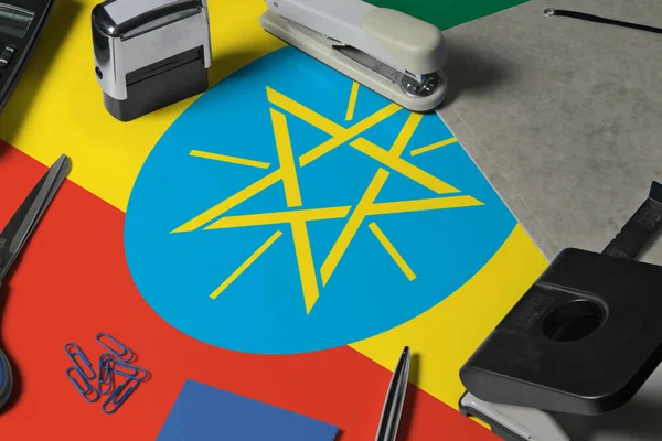 Ethiopia flag with office clerk workplace background. National stationary concept with office tools.
