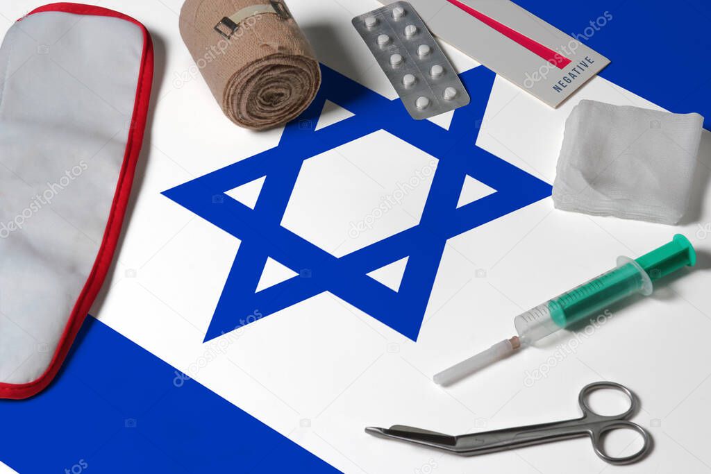 Israel flag with first aid medical kit on wooden table background. National healthcare system concept, medical theme.