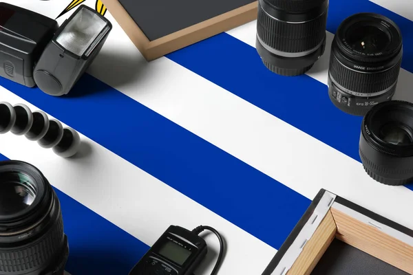 白い木製のテーブルの上に個人的な写真家の機器やツールのトップビューでウルグアイの国旗 コピースペース — ストック写真