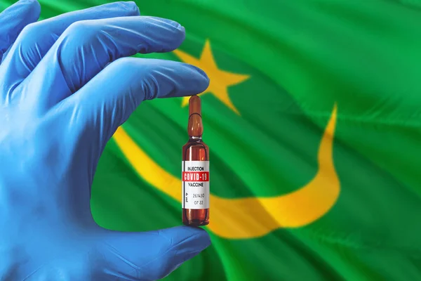モーリタニアはコロナウイルスCovid 19のコンセプトで旗を掲げている 青い保護医療用手袋の医者はワクチンボトルを持っています 流行ウイルス Cov コロナウイルス発生 — ストック写真