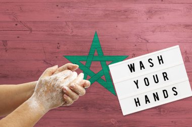 Morocco flag background on wooden surface. Minimal wash your hands board with minimal international hygiene concept hand detail. clipart