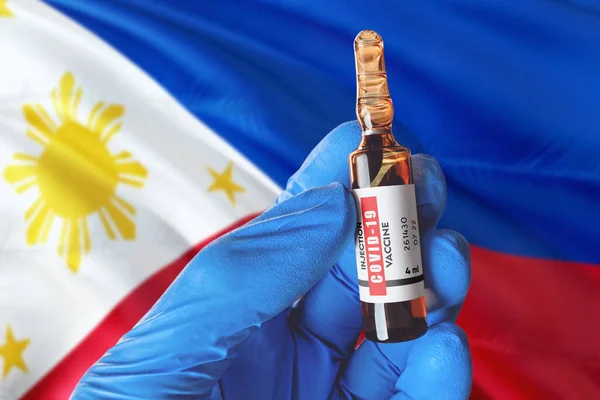 Philippines flag with Coronavirus Covid-19 concept. Doctor with blue protection medical gloves holds a vaccine bottle. coronavirus covid 19 vaccine research.